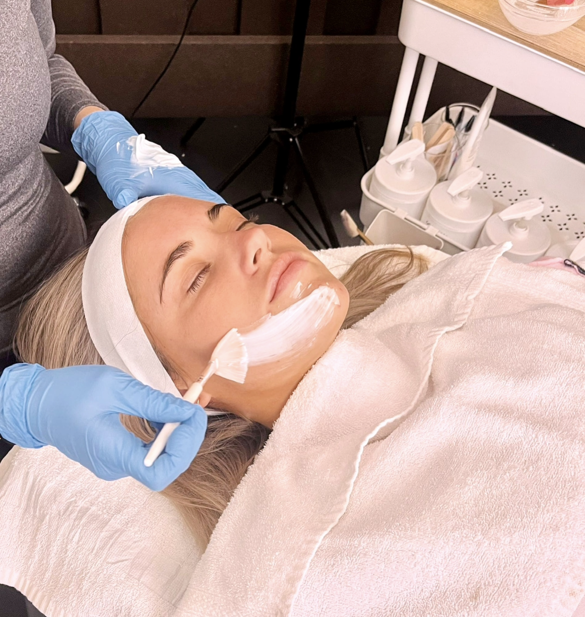 A Shine esthetician brushing a treatment mask onto a client's face
