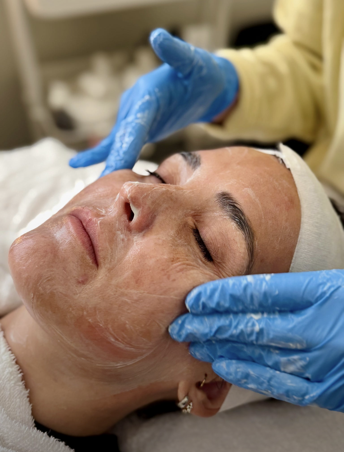 A Shine esthetician applying a treatment mask during a facial