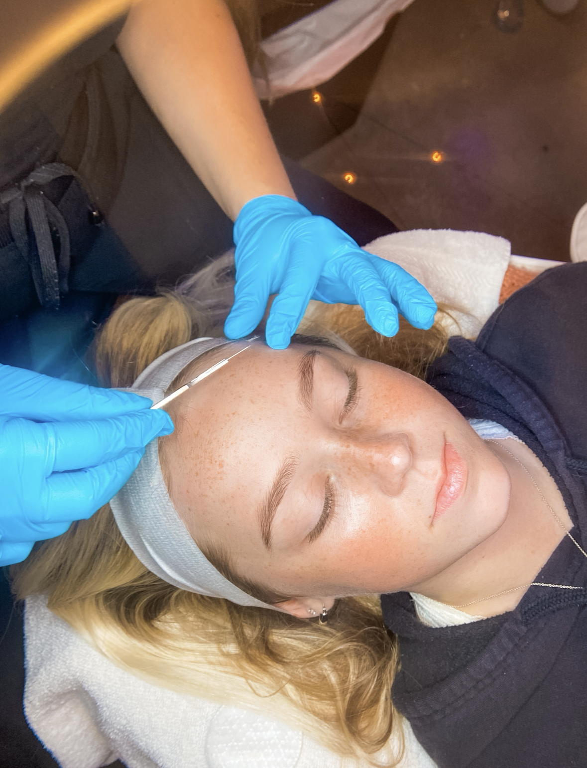 Esthetician performing a dermaplane treatment on a client at Shine