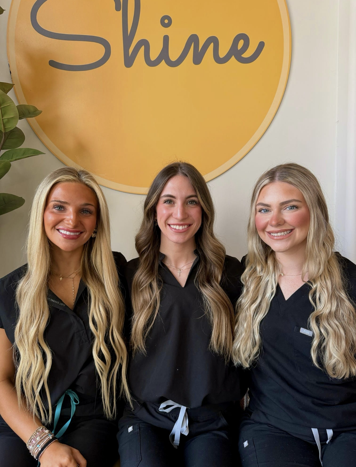 Three Shine Starkville estheticians smiling in front of the Shine Facial Bar sign